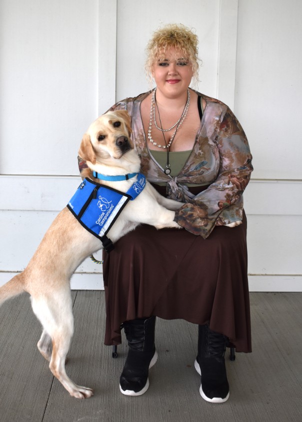 woman posing with a yellow lab service dog